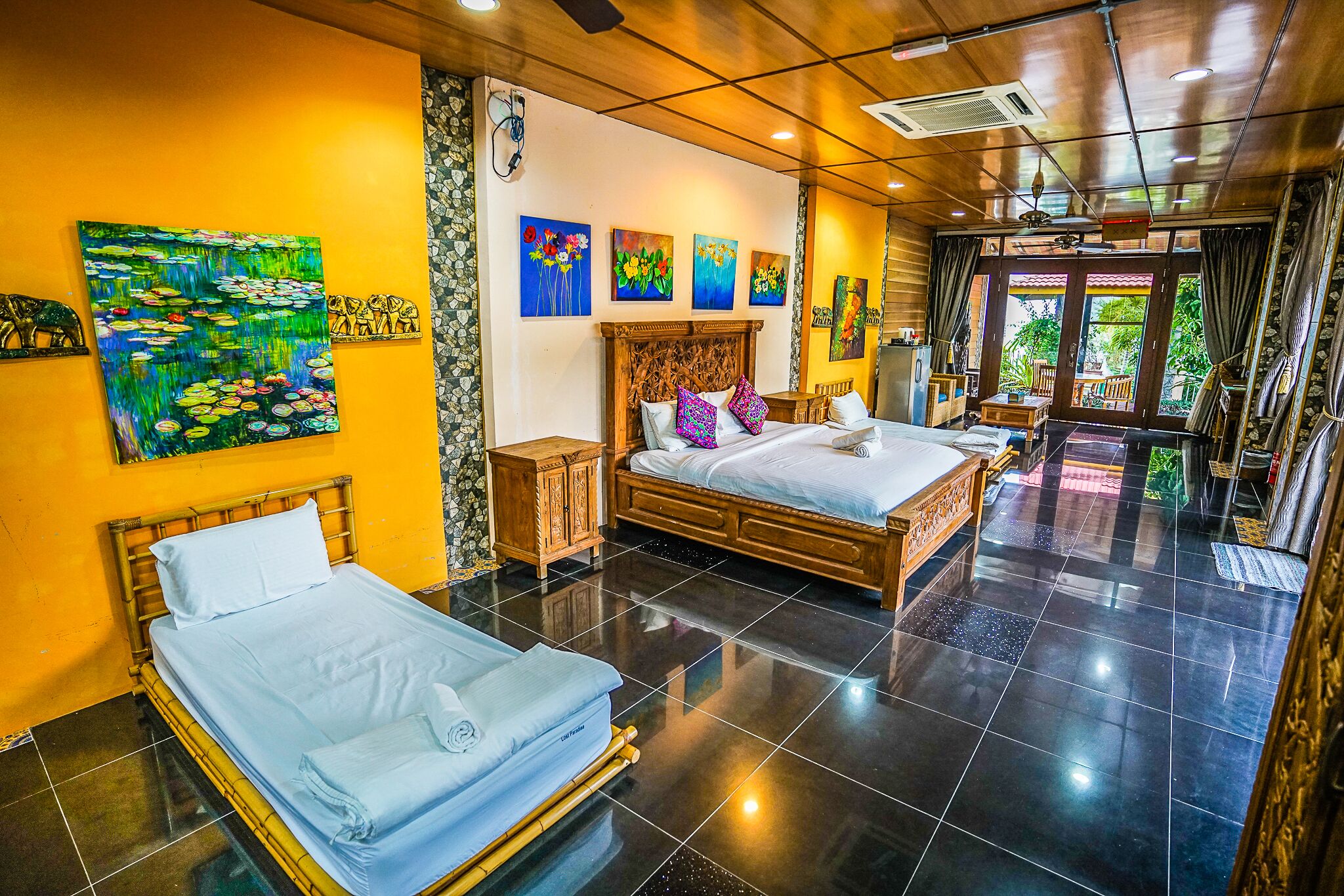 A hotel room with two beds, a wooden headboard, a large window, and artwork on the walls.