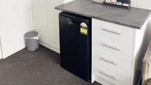 A compact kitchenette with a microwave, a small refrigerator, and a countertop with a trash bin. - Midway Pacifica Lodge (Lower Hutt)