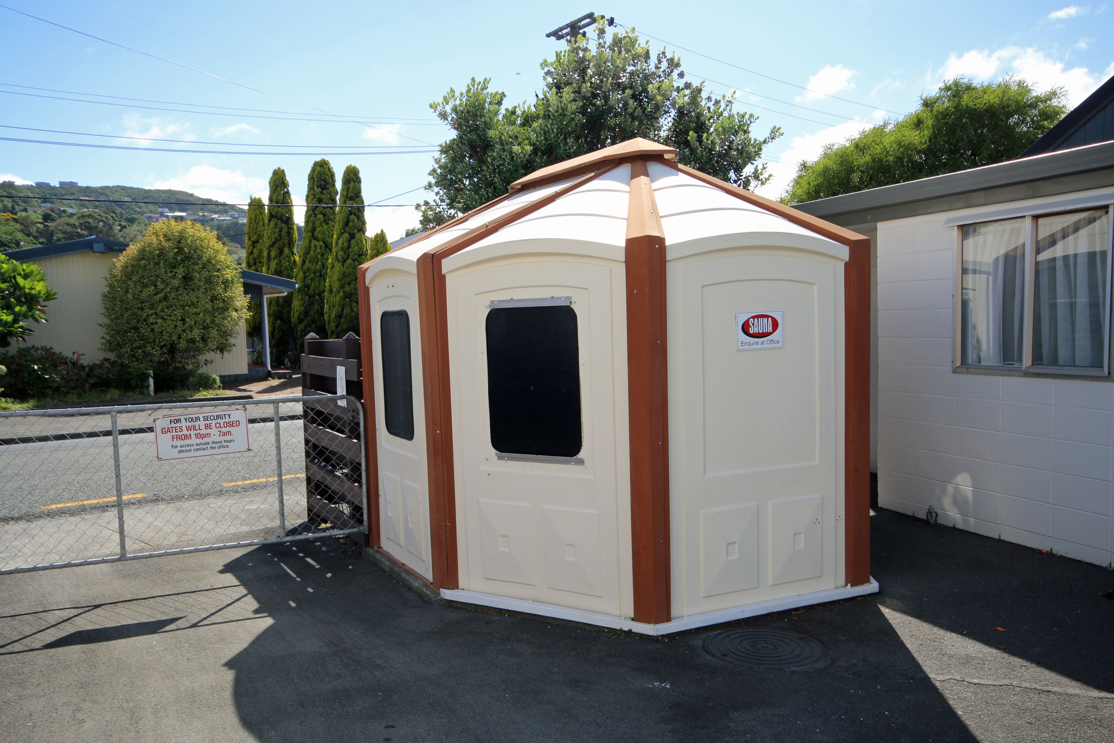 A small, single-story building with a brown roof and white walls, featuring a sign that reads "SAUNA Engines of Office."