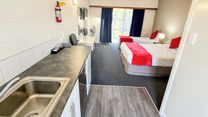A compact hotel room with a kitchenette, two beds, a small bathroom, and a window with curtains. - Midway Pacifica Lodge (Lower Hutt)
