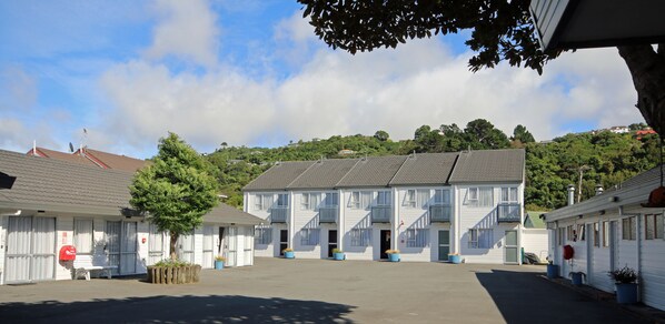 A row of white buildings with balconies, a central entrance, and potted plants. - Midway Pacifica Lodge (Lower Hutt)