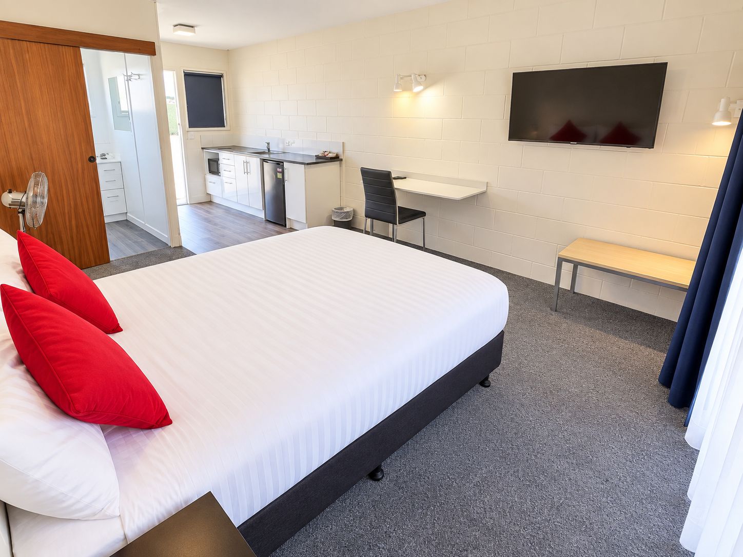 Una habitación de hotel con una cama grande, un escritorio, una silla, un televisor y un banco.