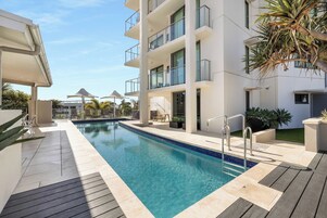 Una piscina al aire libre, sillones reclinables de piscina