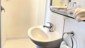 A bathroom with a white sink, a glass shower enclosure, and a towel rack.