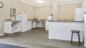 A modern kitchen with white appliances, a wooden countertop, and a built-in island with a stool. - No1 Motels On Victoria (Cambridge)