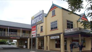 A motel with a signboard, a covered walkway, and a parking area.