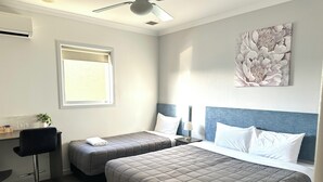 A hotel room with two beds, a desk, a chair, a ceiling fan, a window with blinds, and a wall-mounted artwork. - No1 Motels On Victoria (Cambridge)