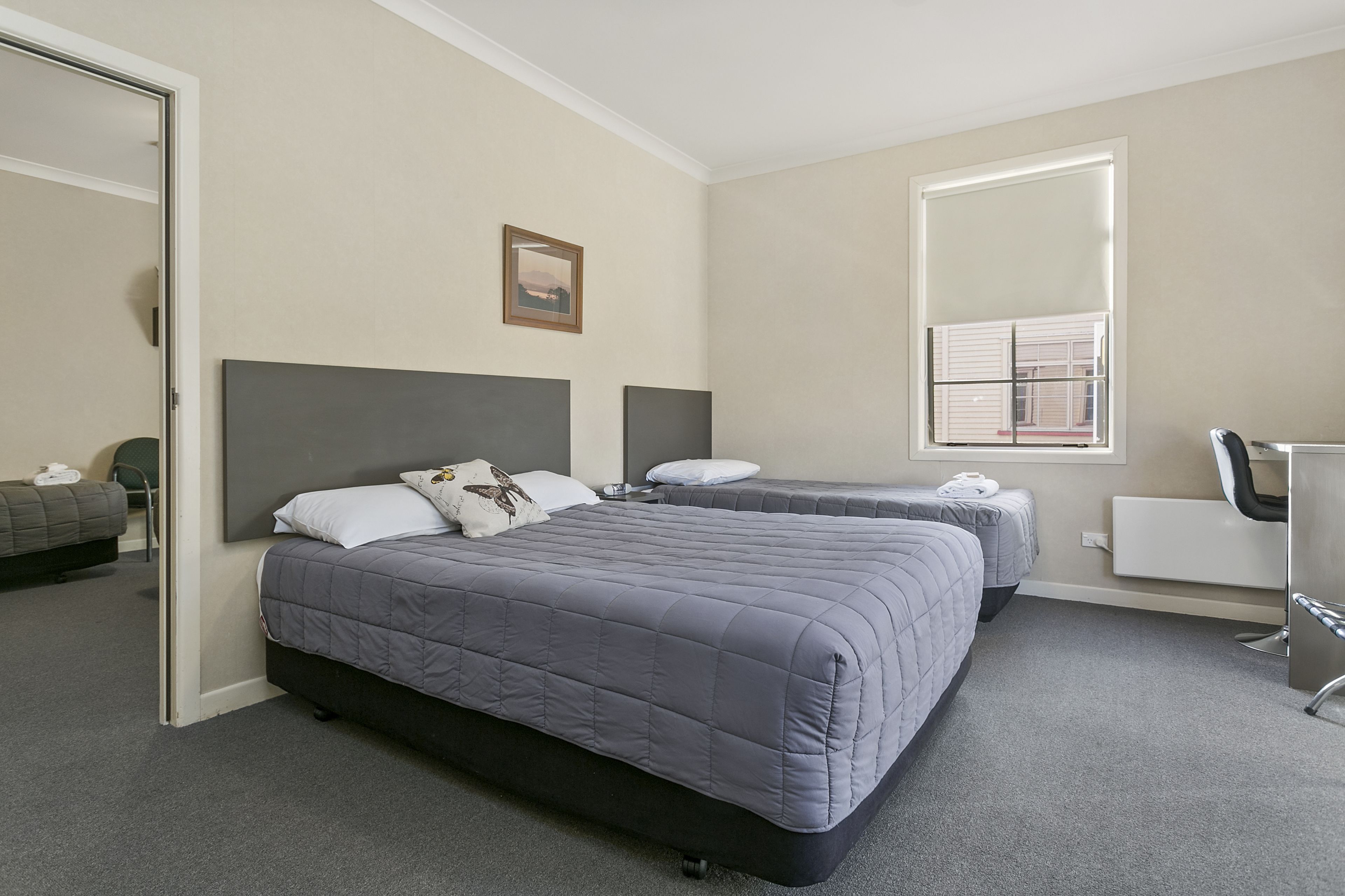 A hotel room with two beds, a desk, and a chair.