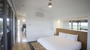 A modern hotel room with a large bed, a wooden bench, and a view of the outdoors. - Barossa Pavilions (Lyndoch)