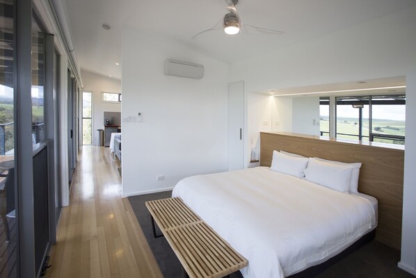A modern hotel room with a large bed, a wooden bench, and a view of the outdoors. - Barossa Pavilions (Lyndoch)