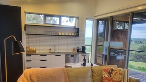 A modern living room with a sofa, a coffee table, a lamp, and a view of the outdoors. - Barossa Pavilions (Lyndoch)