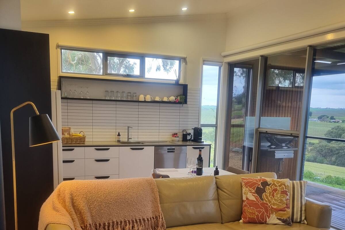 A modern living room with a sofa, a coffee table, a lamp, and a view of the outdoors.