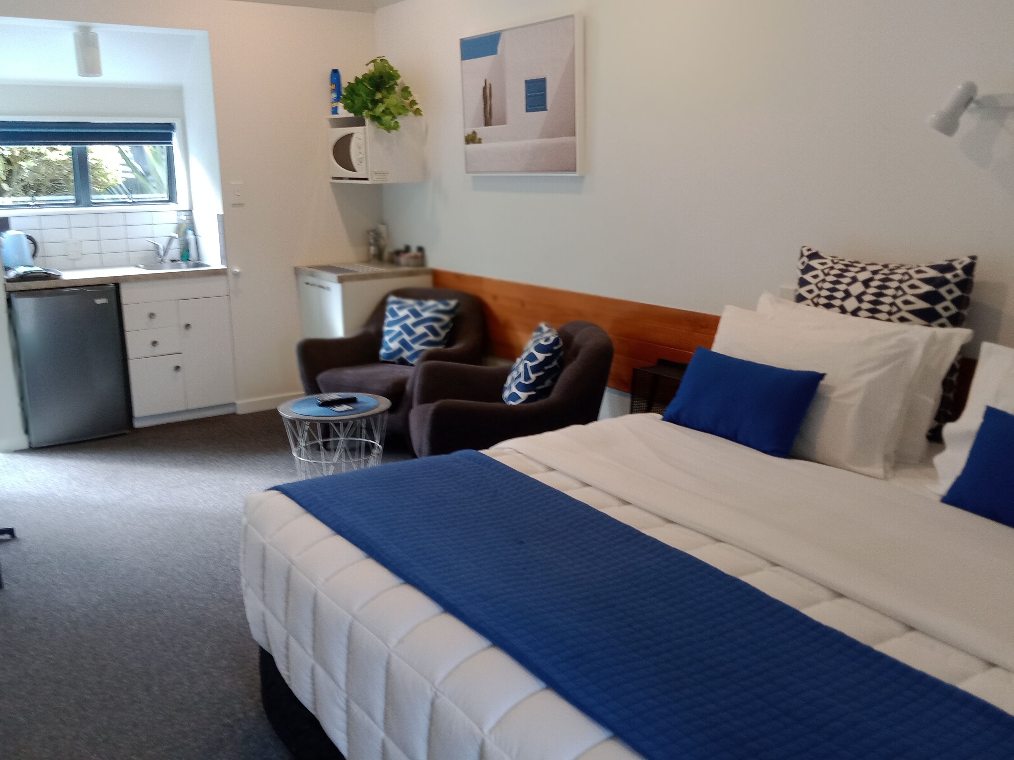 A hotel room with a bed, a chair, a small table, a microwave, and a sink.