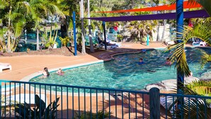 A pool area with a blue fence, palm trees, and lounge chairs. - Main Beach Tourist Park (Main Beach)