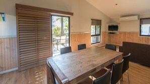 A modern kitchen with wooden cabinets, a large wooden table, and a dining area with chairs. - Main Beach Tourist Park (Main Beach)
