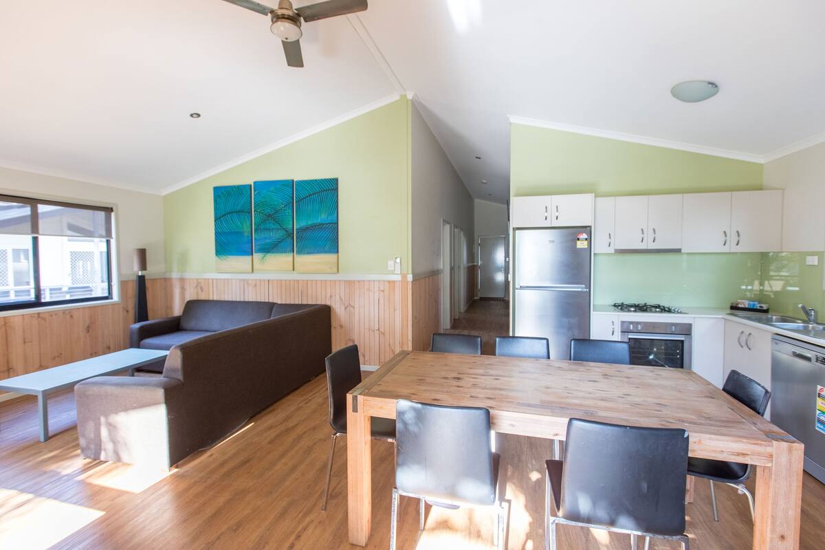A modern kitchen with wooden cabinets, a dining table, and a built-in oven.