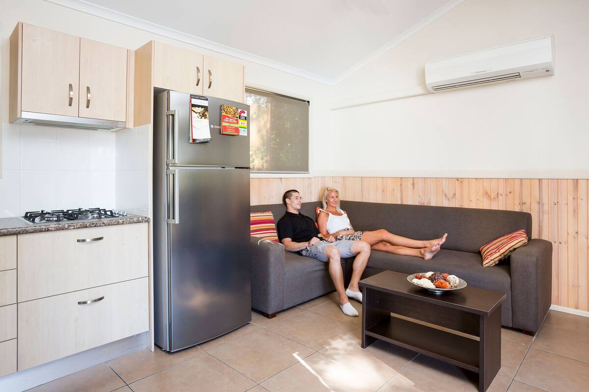 A modern kitchen with a stainless steel refrigerator, wooden cabinets, and a gas stove.
