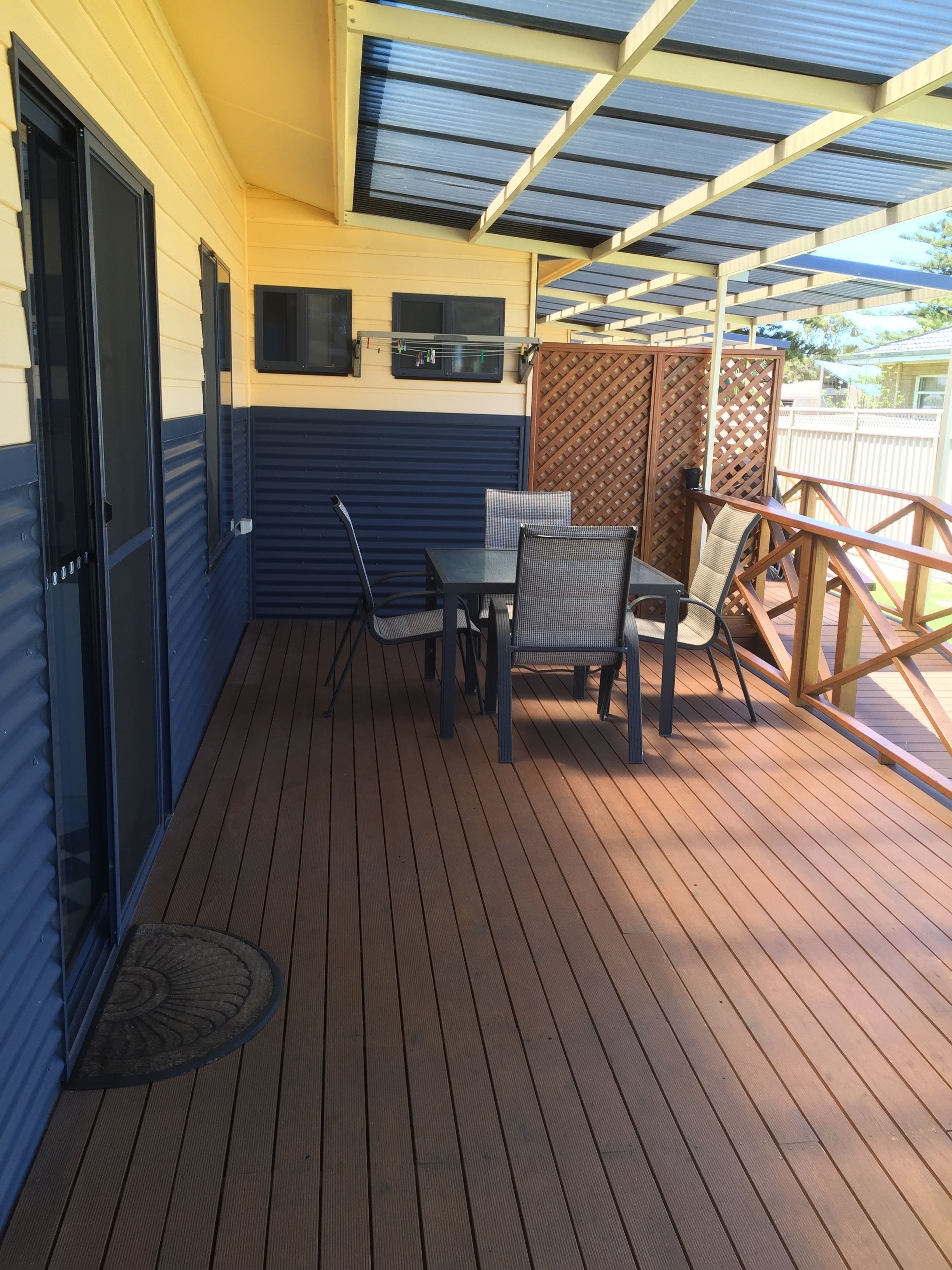 A covered patio with a table and chairs, a door, and a view of the backyard.