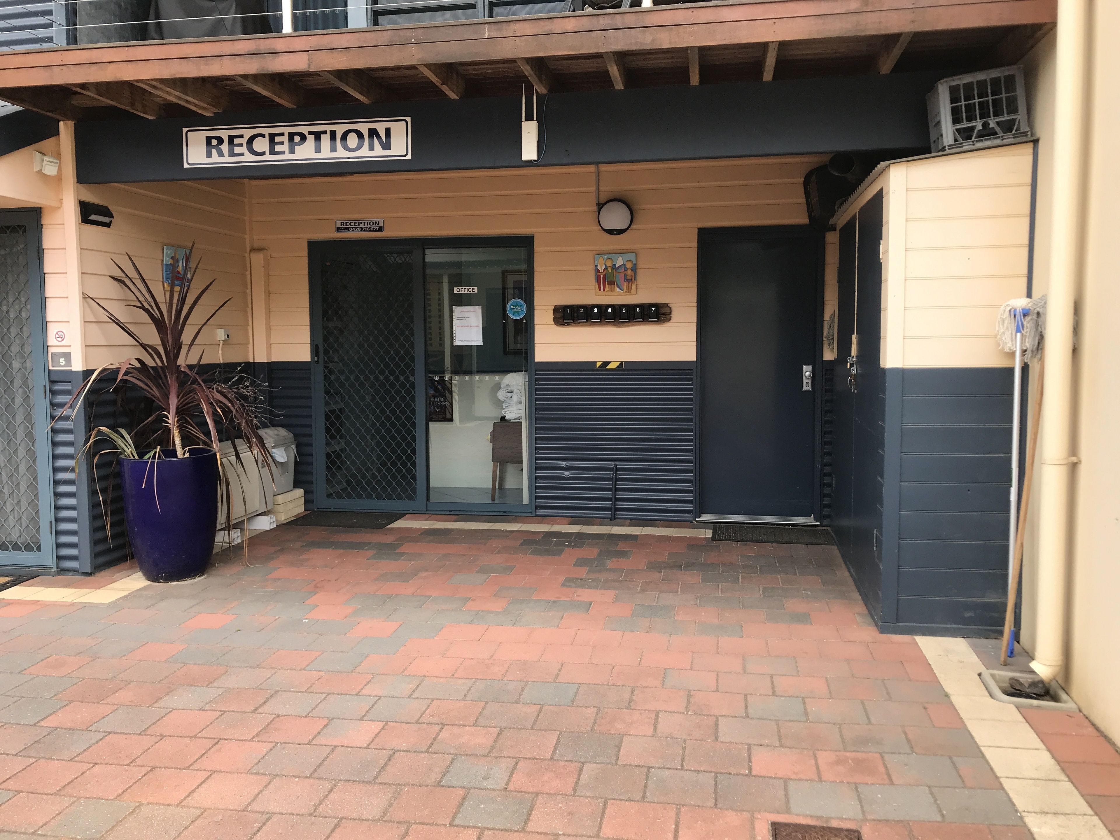 A reception area with a sign, a potted plant, and a closed door.