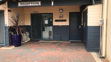 A reception area with a sign, a potted plant, and a closed door.