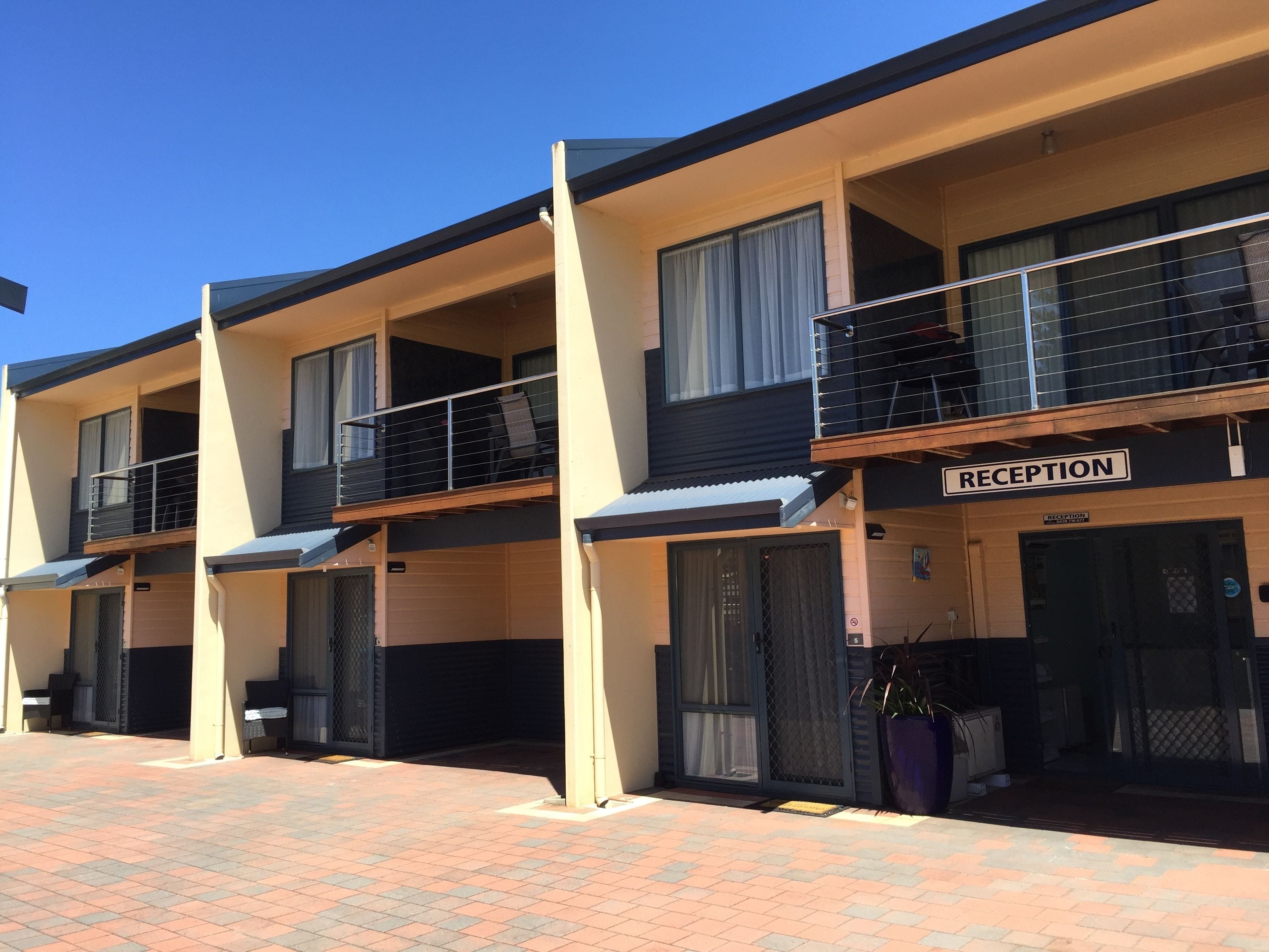A row of two-story buildings with balconies, a reception area, and a paved walkway.