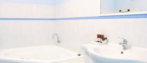 A bathroom with a bathtub, a sink, and a mirror.