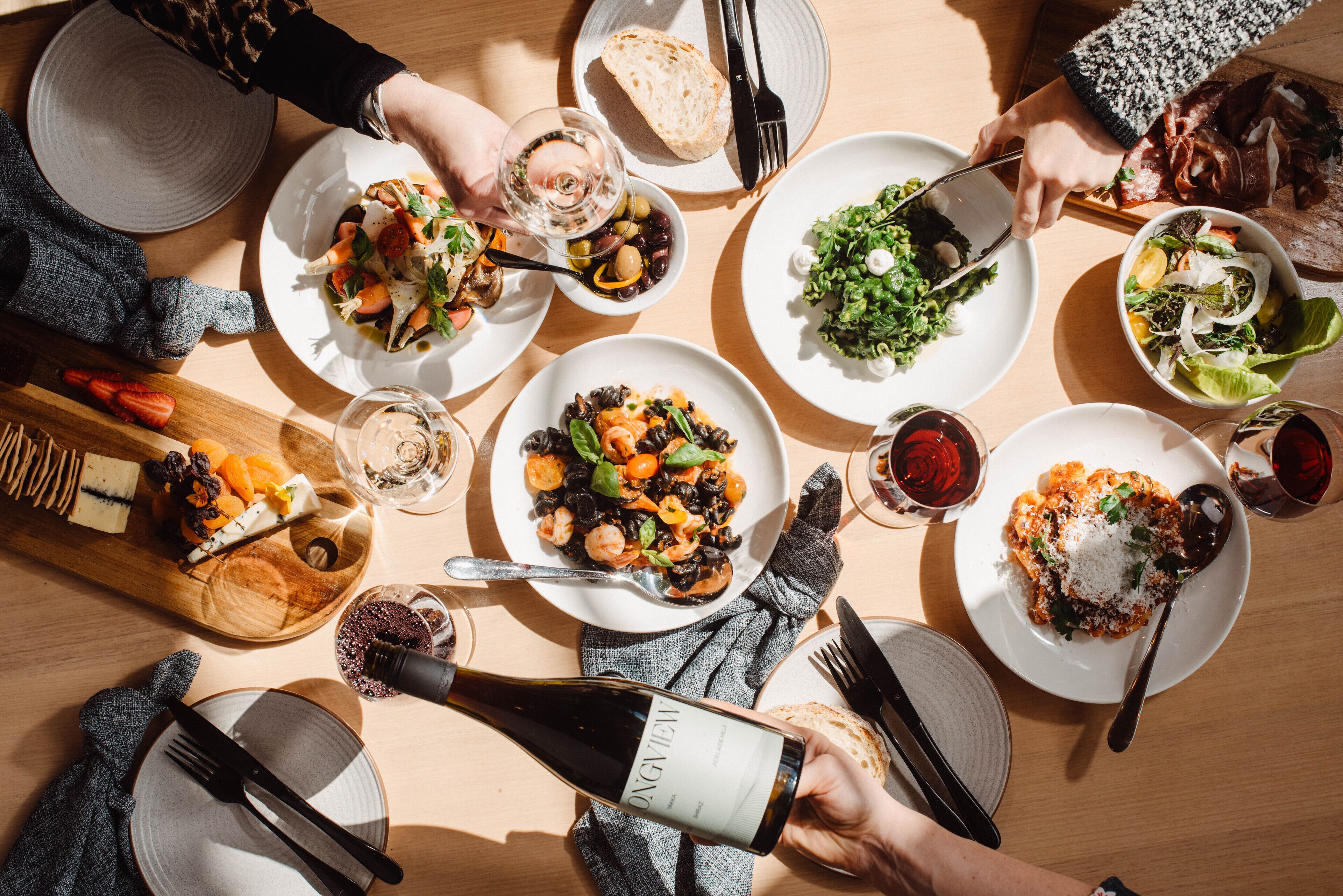 Una mesa de comedor con diversos platos, cubiertos y una botella de vino.