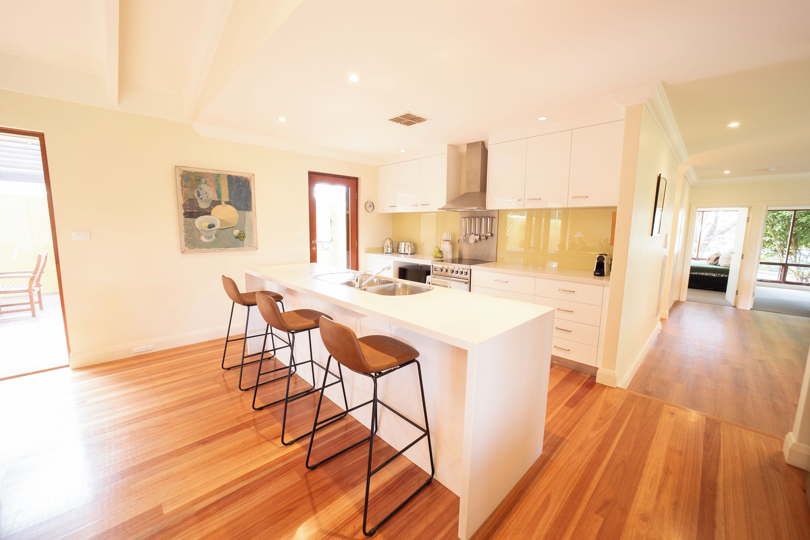 A modern kitchen with a central island, bar stools, and a dining area.