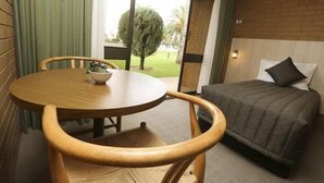 A hotel room with a bed, a round wooden table with a bowl, and a view of a garden. - River City Motel (Mildura)