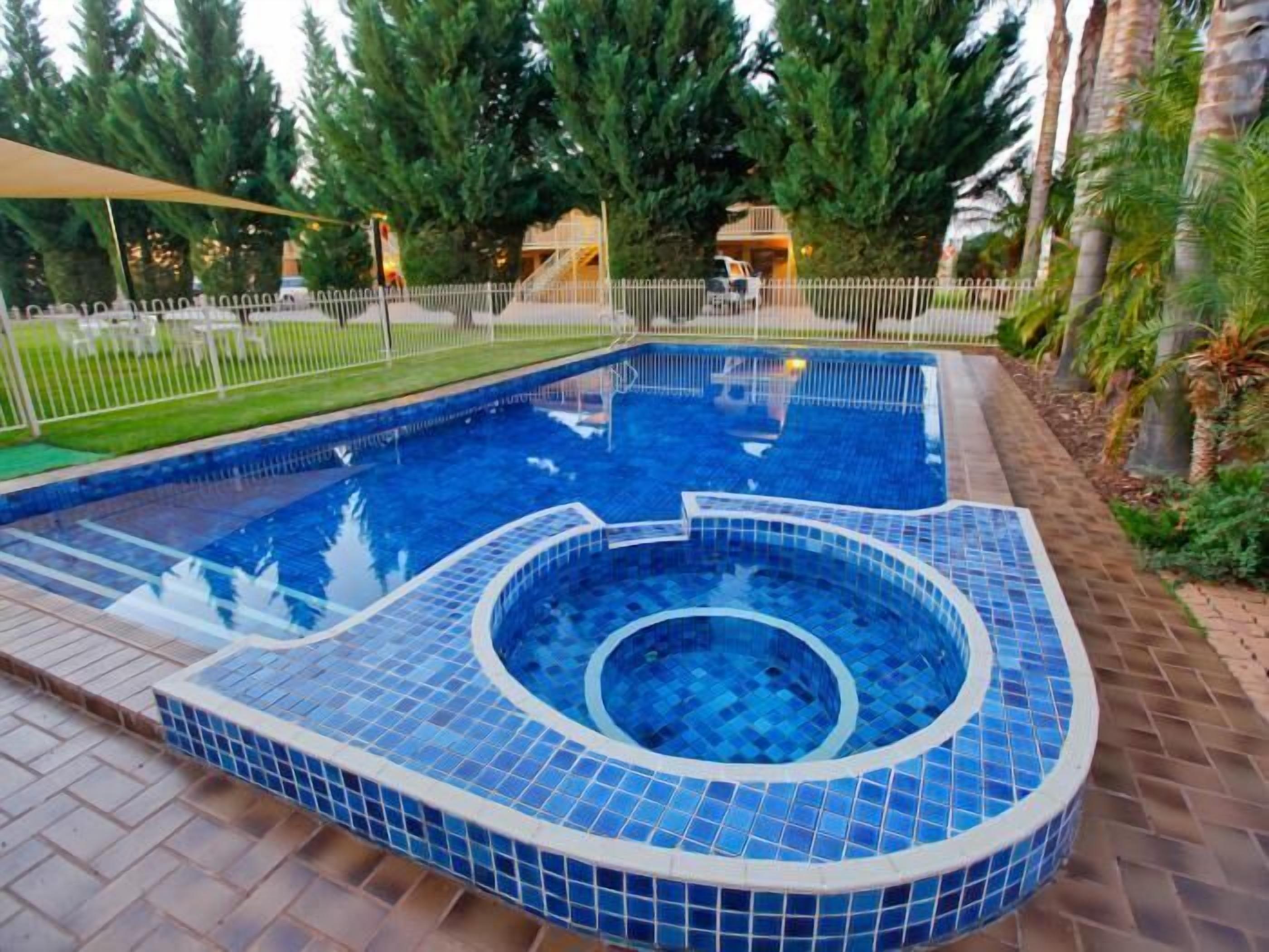 A swimming pool with a tiled edge and a hot tub area.