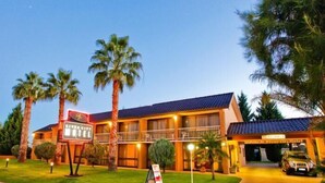 A hotel with a two-story structure, a balcony on the second floor, and a parking area with a vehicle. - River City Motel (Mildura)