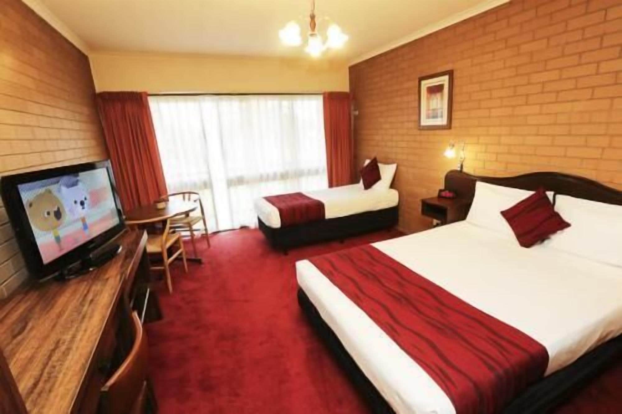 A hotel room with two beds, a TV, and a desk.