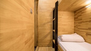 A wooden room with a bunk bed, a small door, and a light fixture. - Box Hotel (Hanoi)