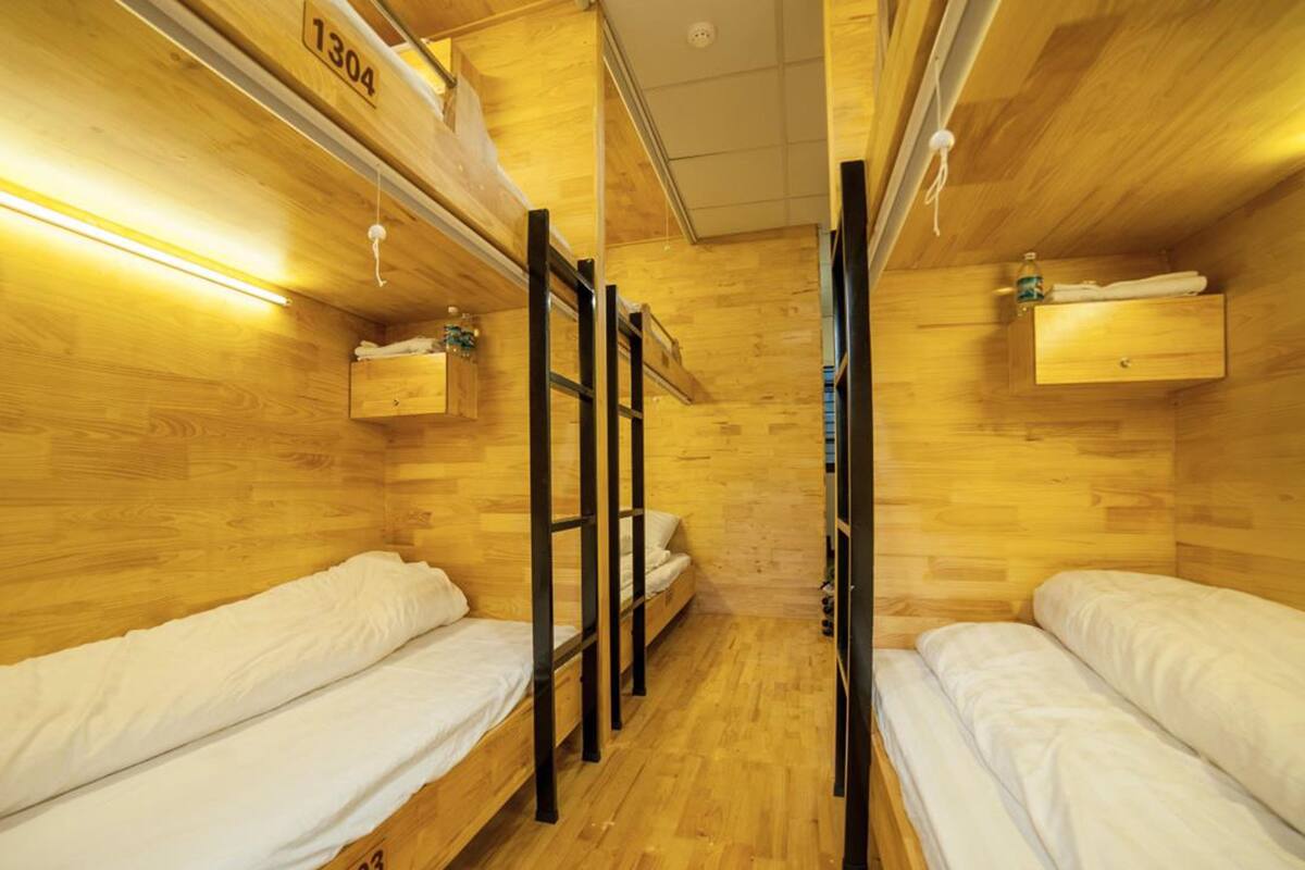 A compact, wooden-themed room with bunk beds, each labeled with a number.
