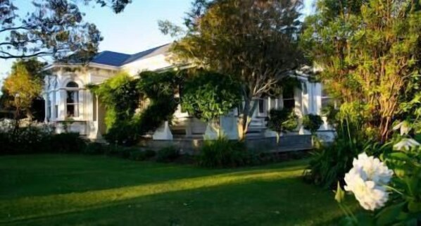A large, two-story house with a well-maintained lawn and garden.