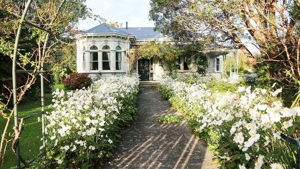 A traditional house with a garden path lined with white flowers leading to a conservatory. - Archer House B&B (Westport)