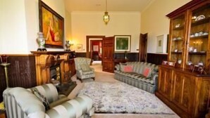 A traditional living room with a sofa set, a patterned rug, and wooden furniture. - Archer House B&B (Westport)