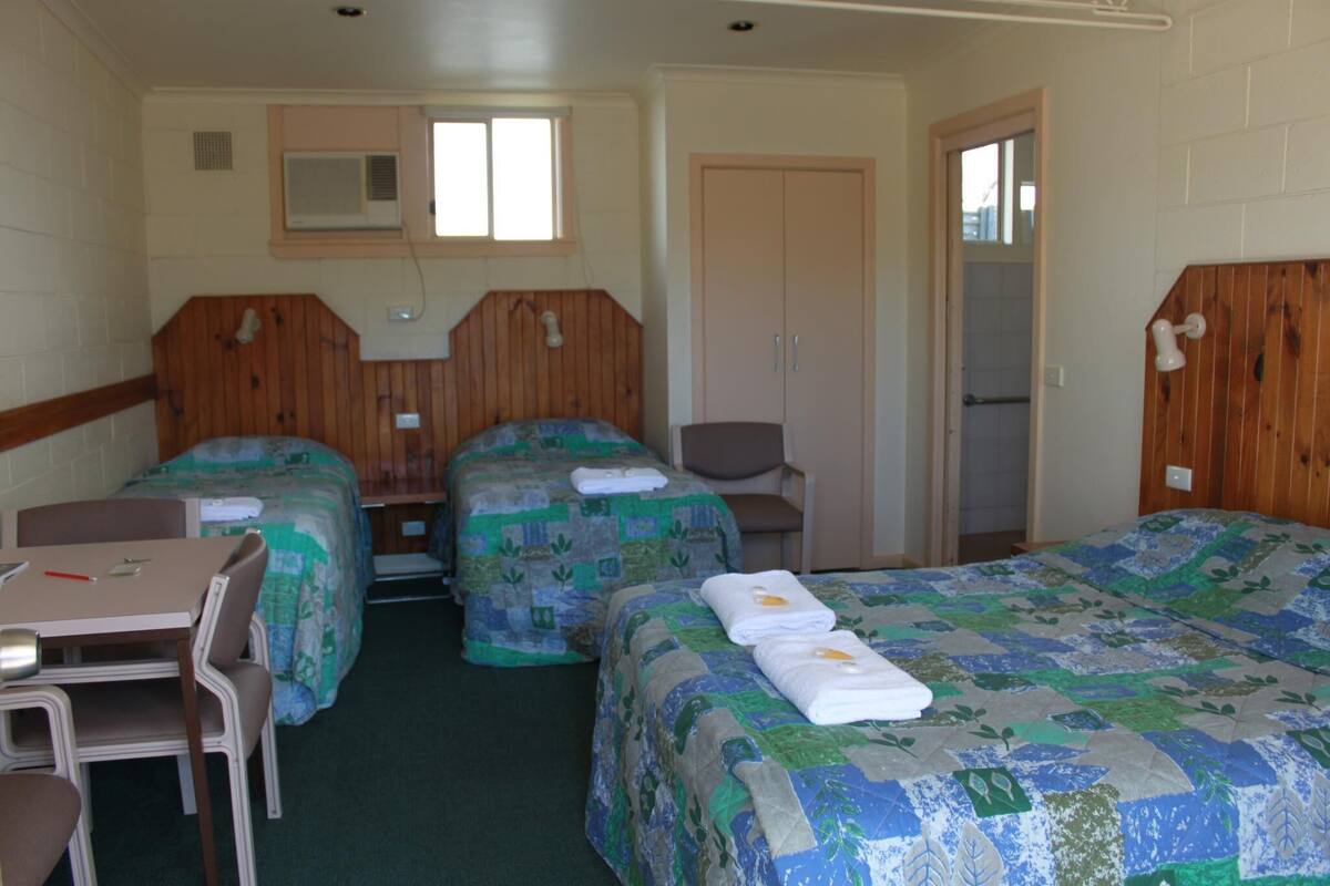 A motel room with two single beds, a small table, and a chair.