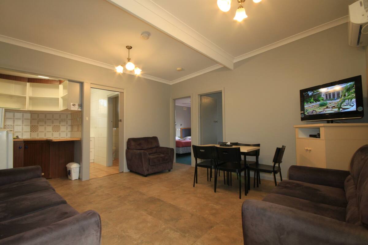 A living room with a TV, a dining table, and a couch.