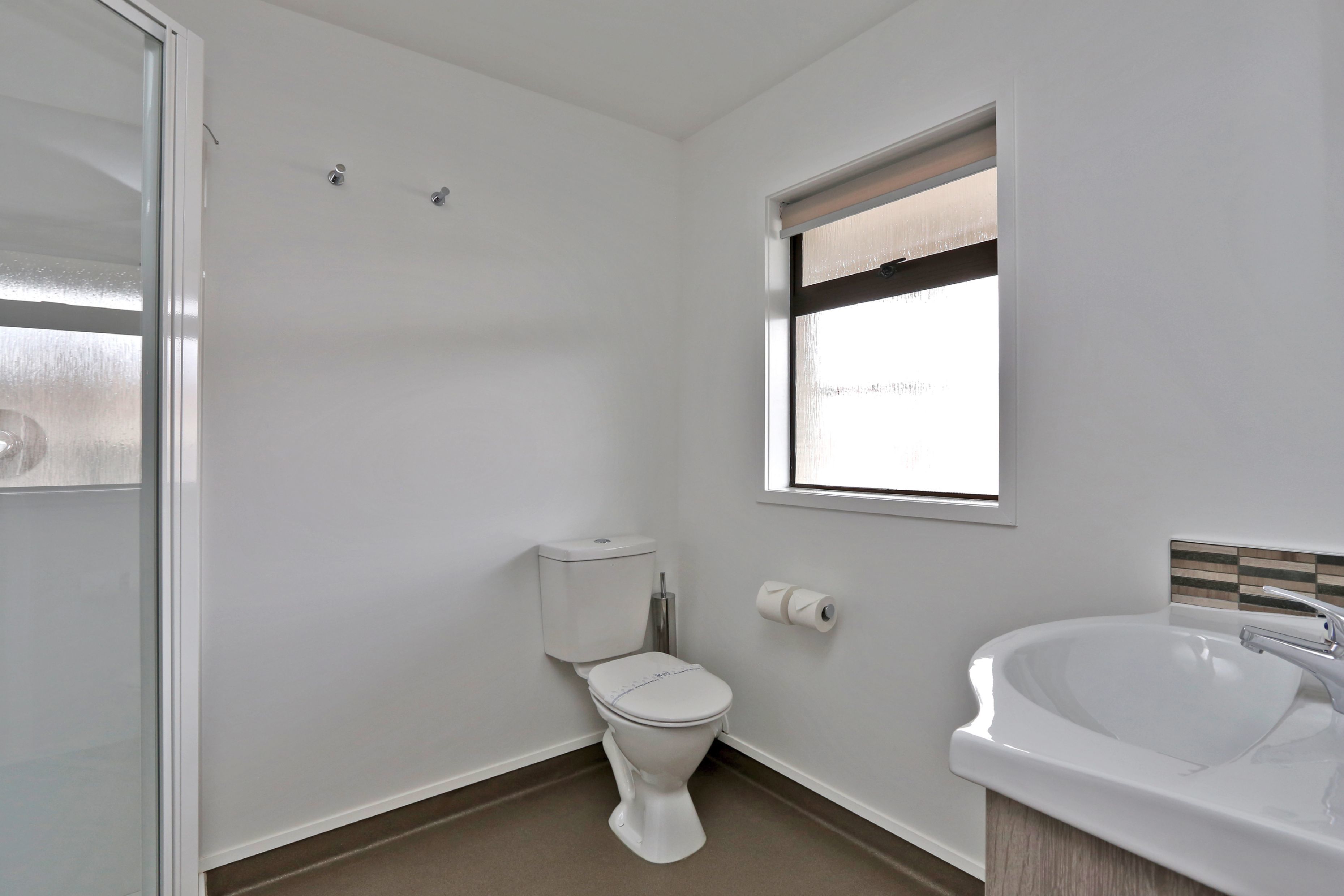 A small, clean bathroom with a toilet, sink, and window.