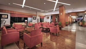 A spacious lobby with a modern design, featuring a mix of seating areas and a reception desk. - Aston Tanjung City Hotel (Murungpudak)