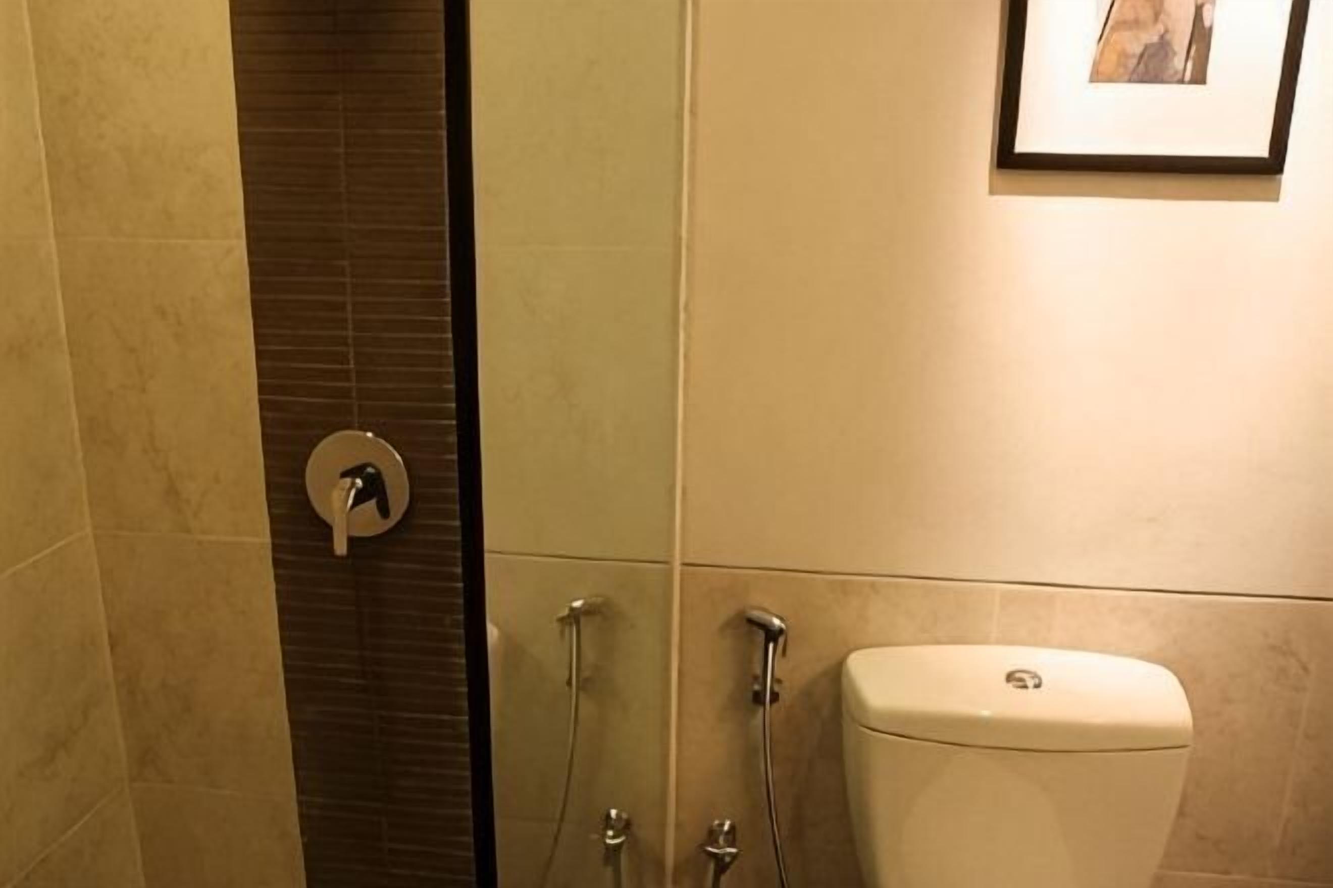 A bathroom with a toilet, a shower, and a wall-mounted picture.