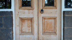 Una puerta doble de madera con un picaporte metálico, ubicada en una pared de piedra.
