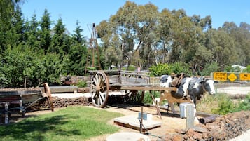 A historical exhibit featuring a wooden cart with a cow, surrounded by rocks and trees.