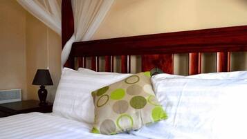 A hotel room with a bed, a nightstand, a lamp, and a canopy bedspread.
