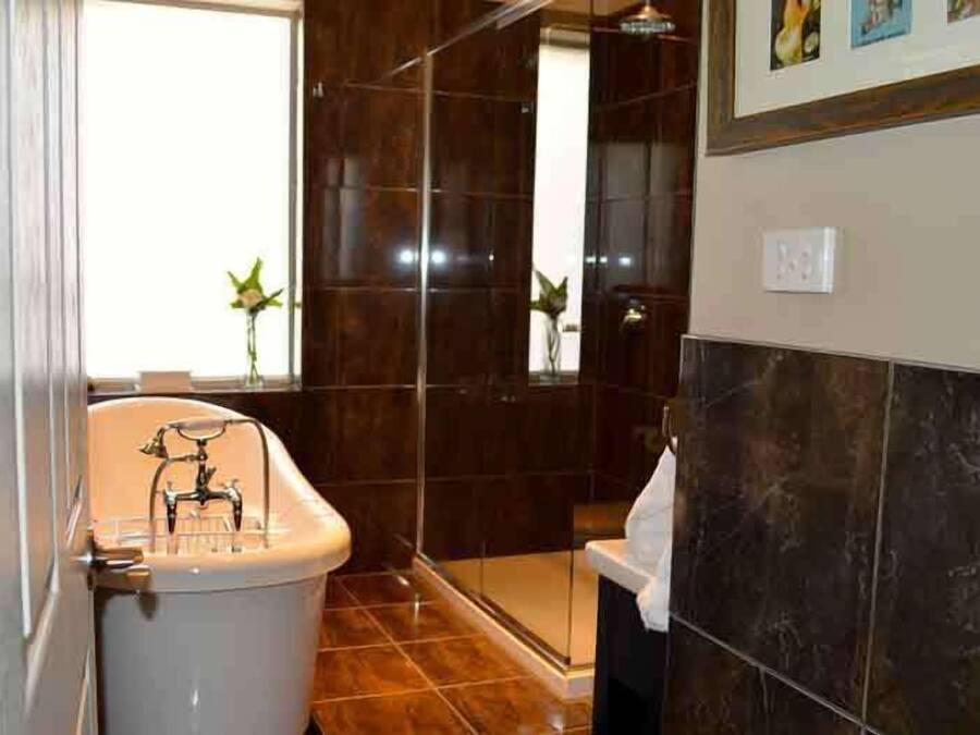 Et badeværelse med badekar, bruser og toilet.