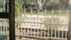 A view through a glass door of a fenced outdoor area with trees and a lamp post. - Tooleybuc Motel (Tooleybuc)