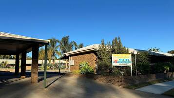 Motel Tooleybuc con fachada de ladrillo, zona de estacionamiento cubierta y cartel que indica disponibilidad.