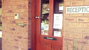 A reception area with a wooden door, a night bell, and a sign indicating office hours. - Tooleybuc Motel (Tooleybuc)
