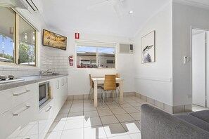 A modern kitchen with white cabinets, a built-in oven, and a window overlooking a cityscape. - Ingenia Holidays Noosa (Tewantin)